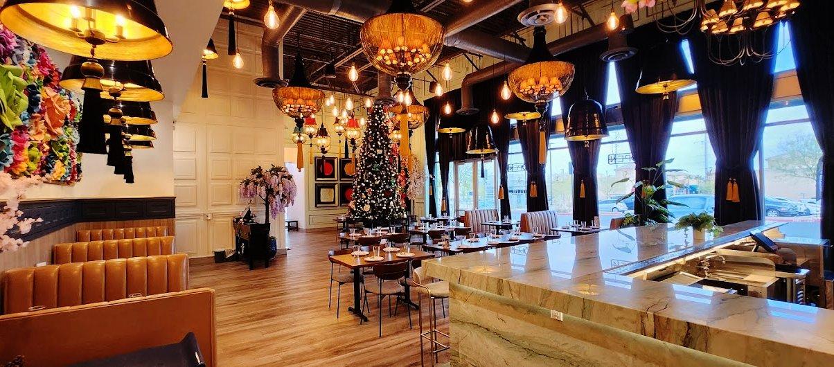 A restaurant with hanging pendant lights, a decorated Christmas tree, marble counter, and floor-to-ceiling windows at Weera Thai - Rainbow.