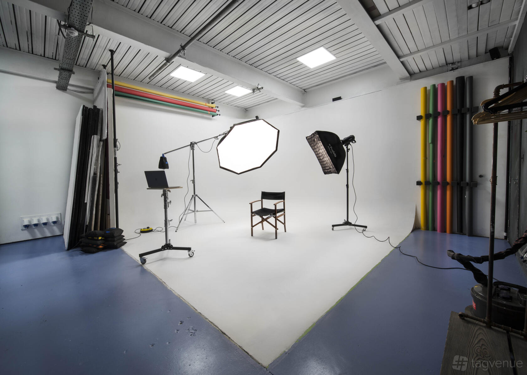 A photo studio with a white cyclorama backdrop, lighting equipment, and colored paper rolls at Shelford Place Studios.