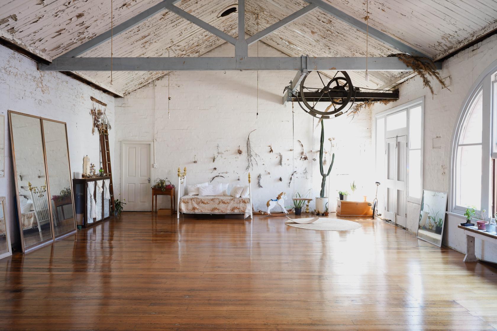 A loft with exposed beams, whitewashed brick walls, large mirrors, and polished wooden floors at CBD.