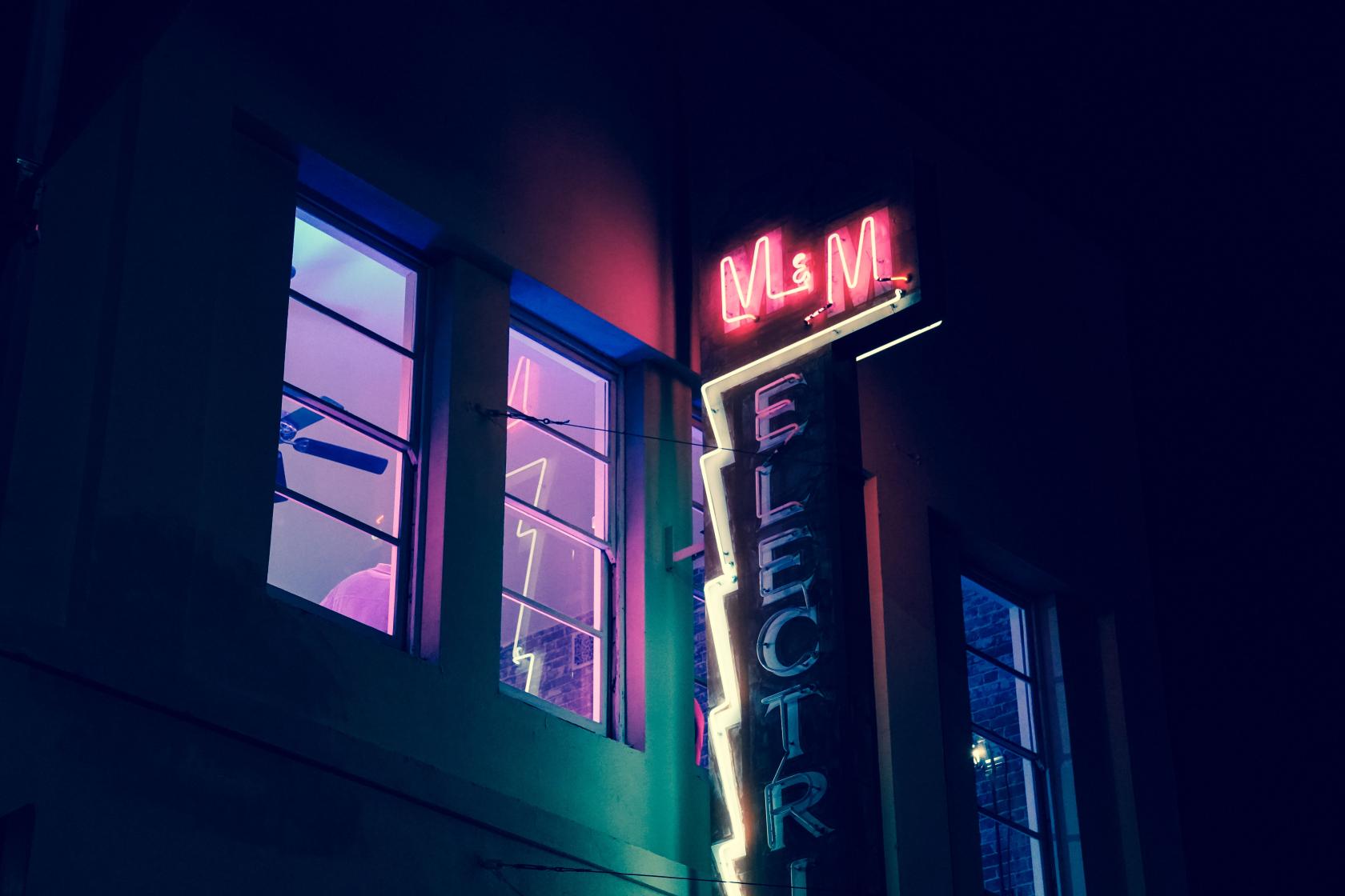 A versatile event space with neon signage and large windows illuminated by colored lights at Electric Loft.