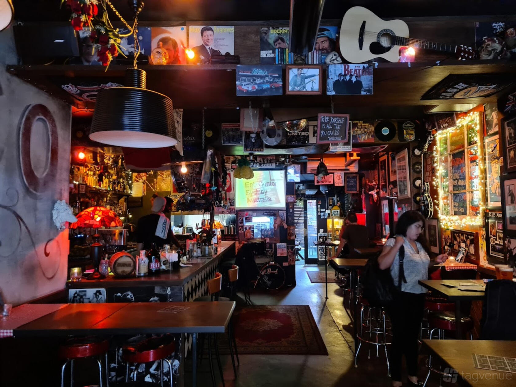 A bar with eclectic decor, vinyl records, neon lighting, and wall art at VASCO Surry Hills.