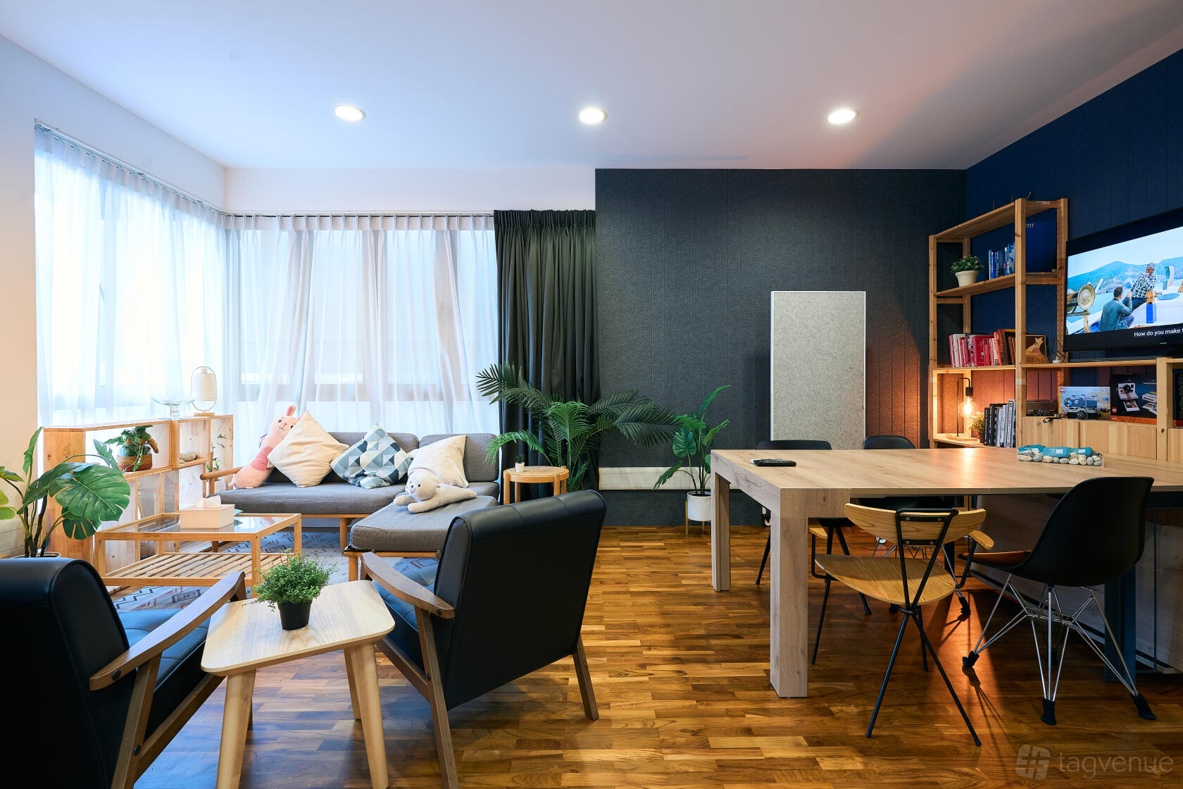 A photo studio with large windows, wood flooring, lounge seating, and a workspace at Minto Studios.