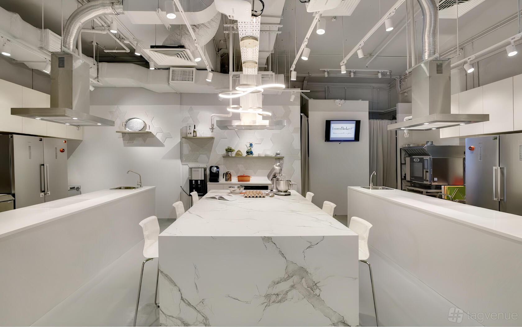 A kitchen with a marble island, stainless steel appliances, open shelving, and overhead lighting at IncuBaker.