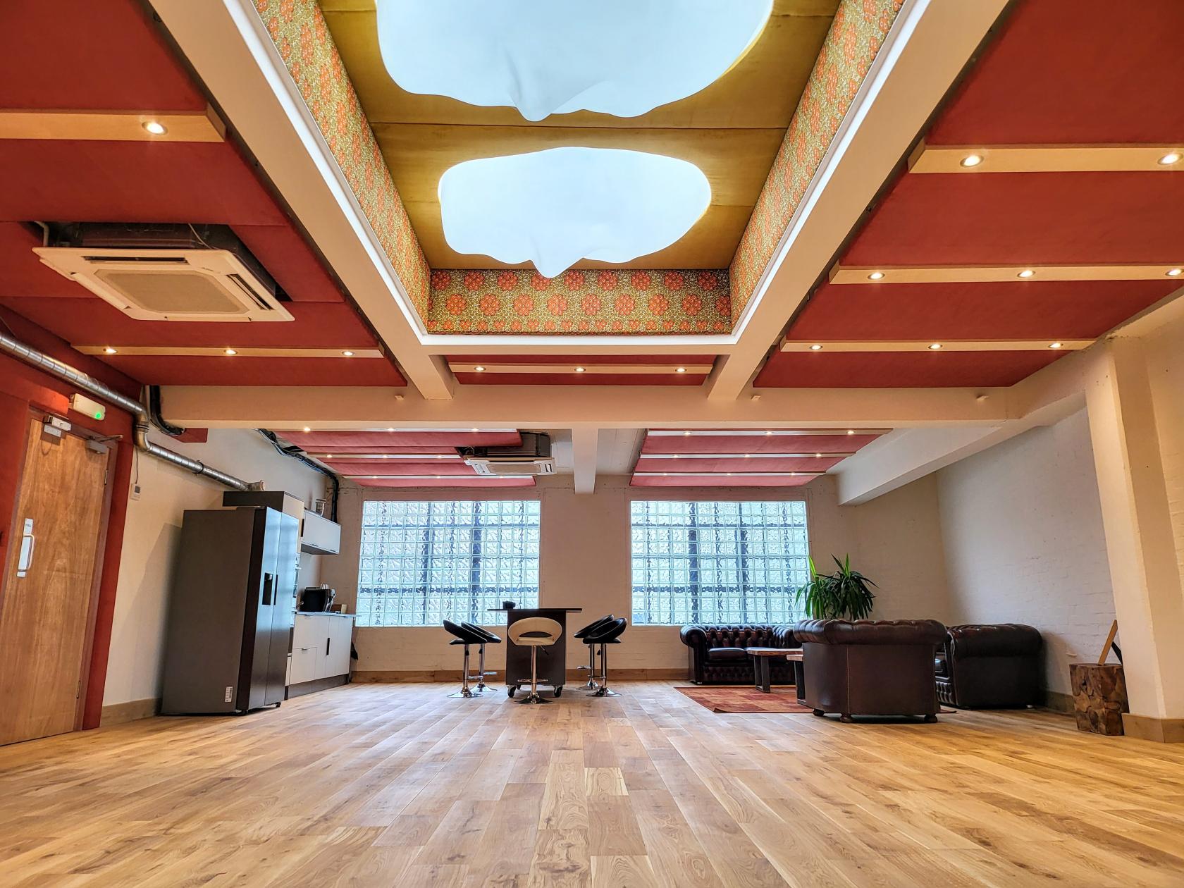 A rehearsal studio event space with wood floors, skylights, exposed brick, and lounge seating at Fomo London Studio.