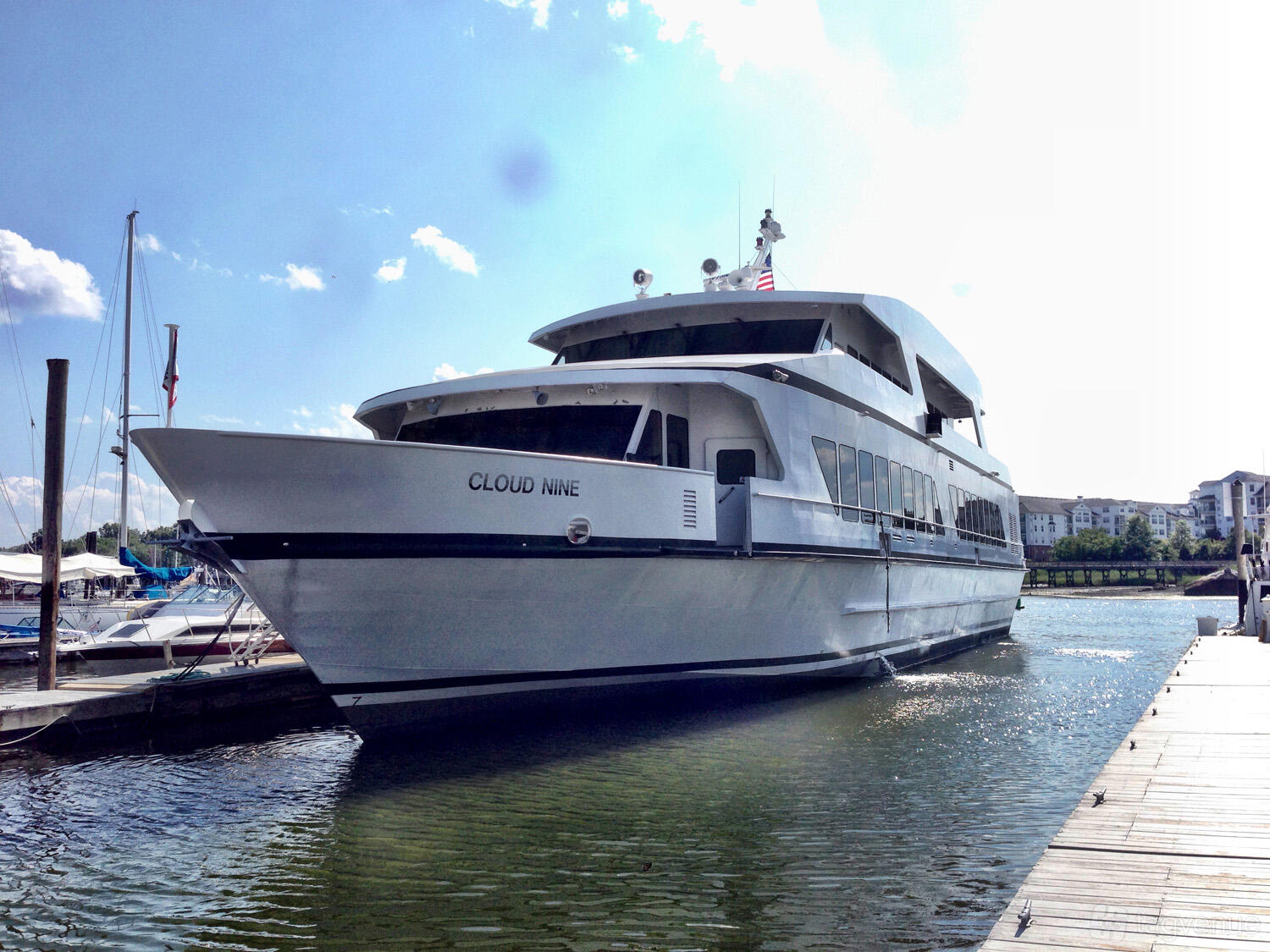 A white multi-level yacht docked at a marina with waterside views at Del Rio Yacht Charter.