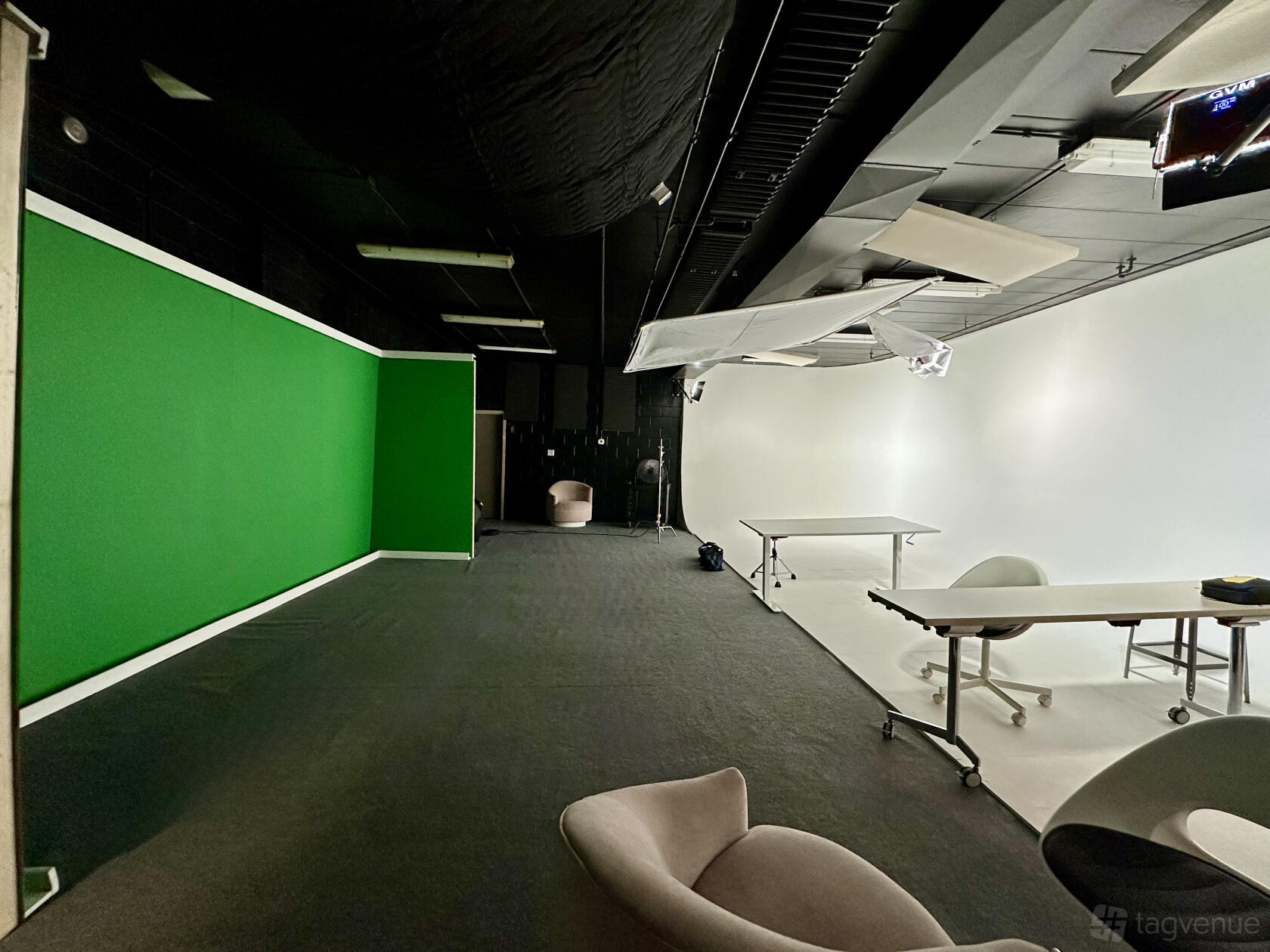 A photo studio with a green screen wall, white cyclorama, and moveable tables at Photo/Video Production Studio.