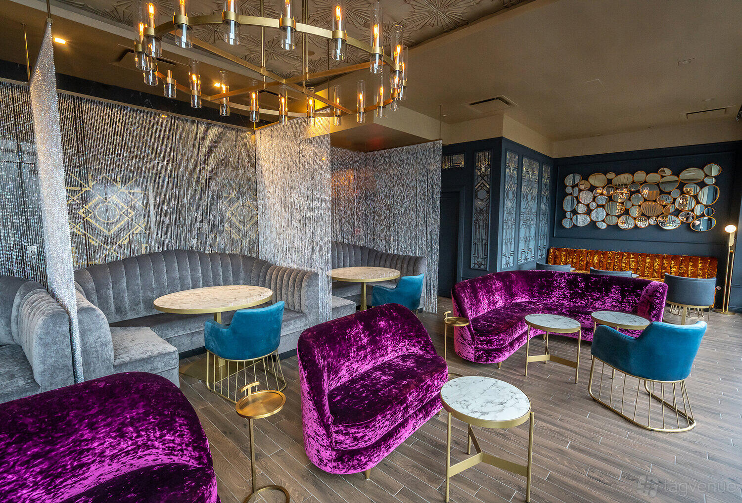 A rooftop cocktail lounge with velvet purple sofas, marble tables, and a chandelier at Dear Irving on Hudson Rooftop.