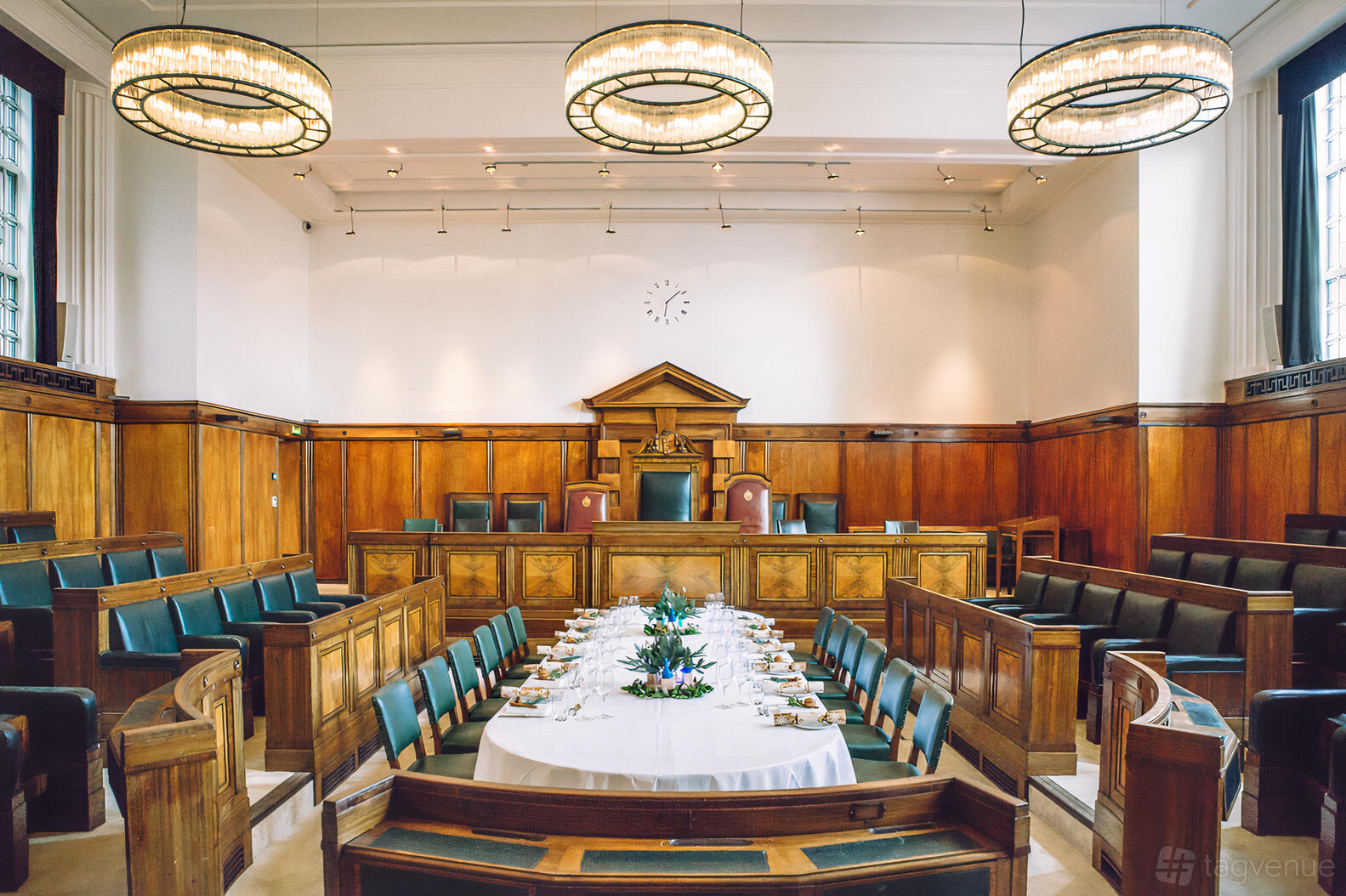 A function room with wood-paneled walls, green leather seating, and a large oval dining table at Town Hall Hotel.