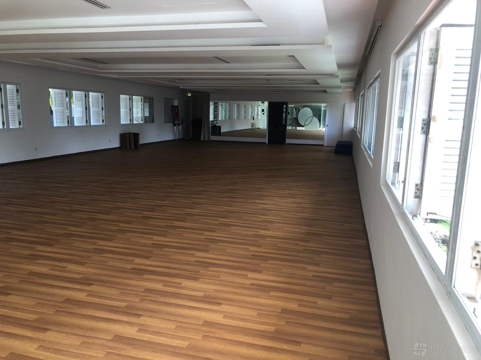 A meeting room with wood flooring, full-length mirrors, and large windows at FOCUS Adventure Facility.