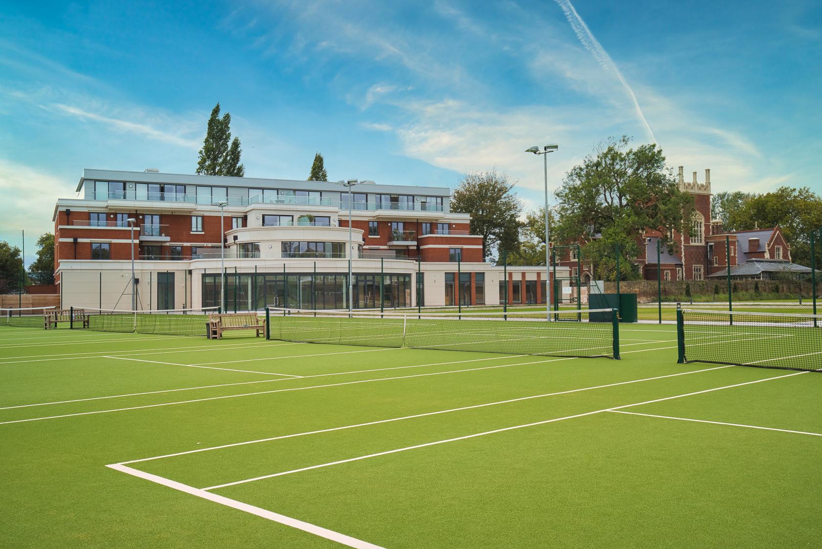 A historic building with multiple outdoor tennis courts and clubhouse seating at Parsons Green Club.