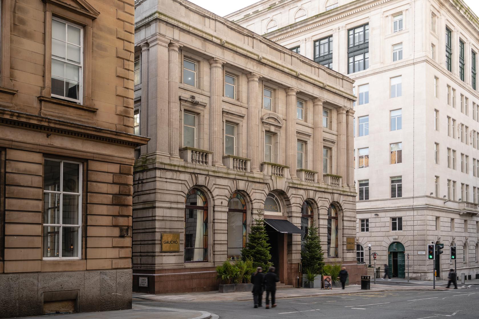 A restaurant with a classic stone facade, arched windows, and a black awning at Gaucho Liverpool.