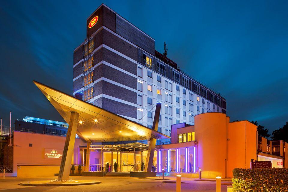 A hotel with a glass canopy entrance and illuminated exterior lighting at Crowne Plaza London Gatwick.
