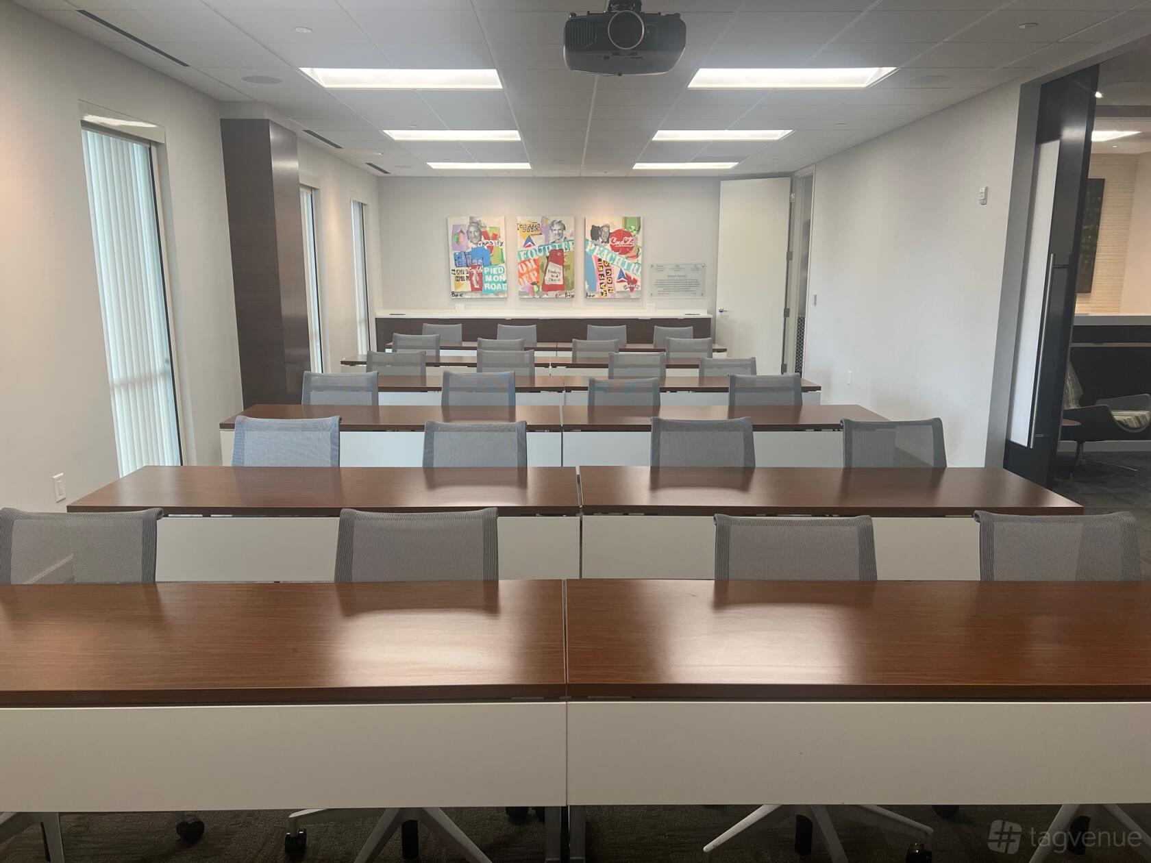A meeting centre with rows of wooden tables, mesh chairs, and colorful artwork on the wall at AOS Learning Center.