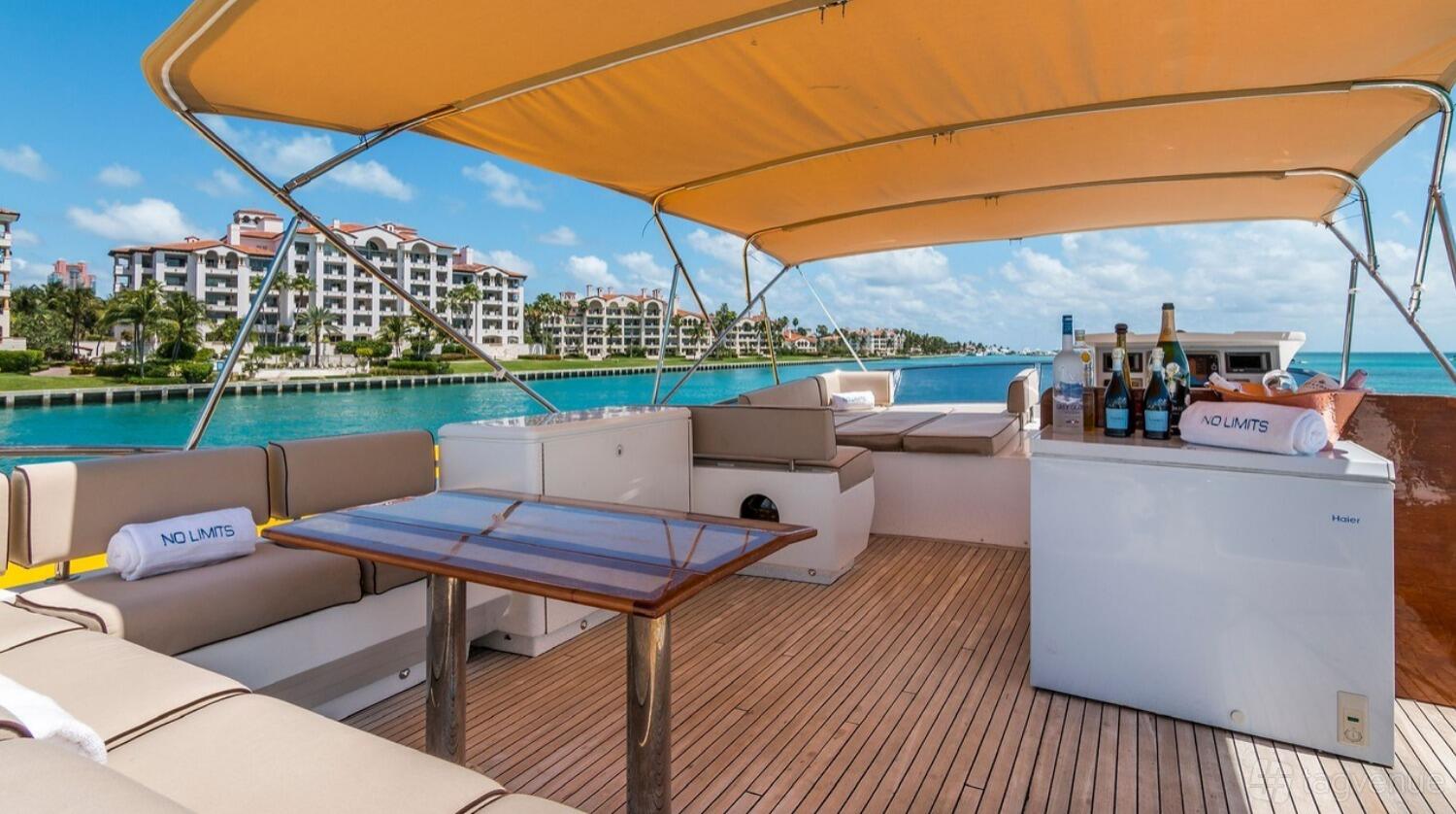 A charter boat deck with cushioned bench seating, wood flooring, and a table under a yellow canopy at Luxe Charters.
