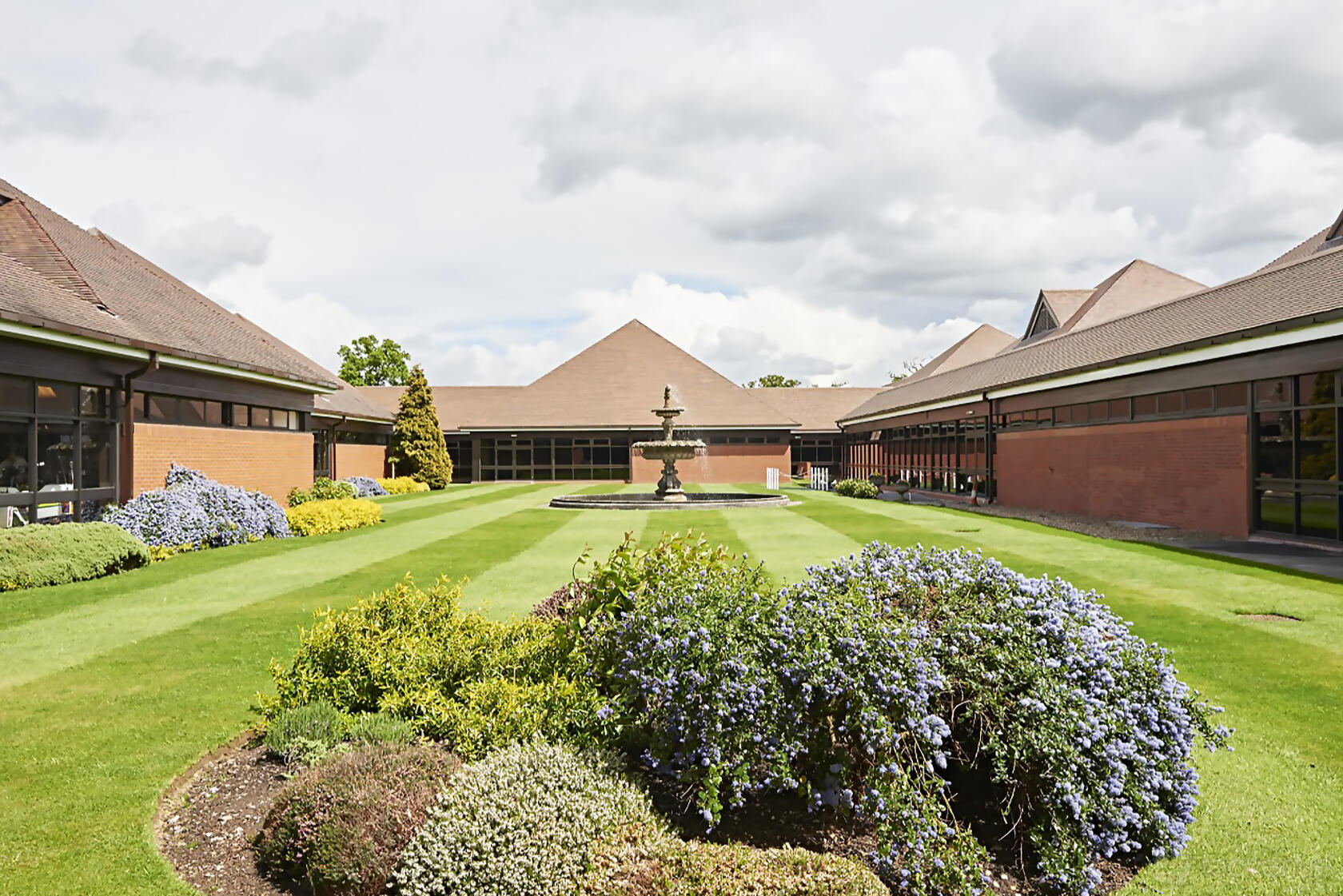A conference centre with landscaped gardens, manicured lawns, and a central fountain at National Motorcycle Museum.