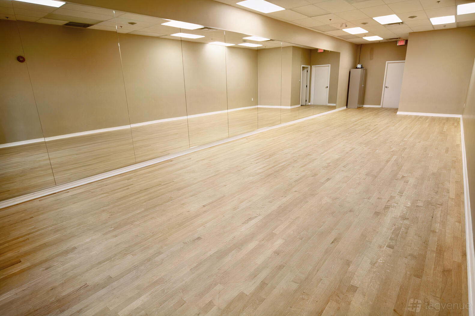 A rehearsal studio with mirrored walls, wood floors, and recessed ceiling lights at ViBE Dance Studio.
