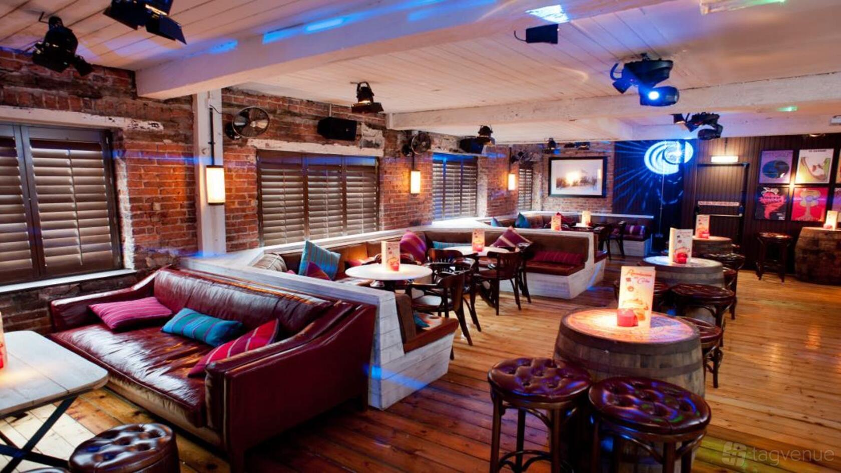 An event space in a bar with exposed brick walls, leather sofas, and wood floors at Revolution Leeds Call Lane.