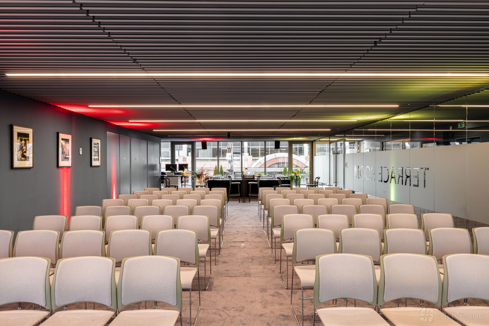A function room with rows of beige chairs, dark slatted ceiling, and floor-to-ceiling windows at Events at No6.