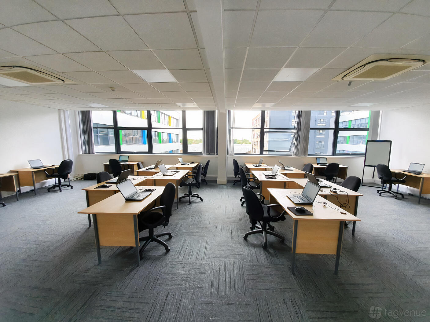 A training room with rows of desks, office chairs, laptops, and large windows at ITTS.