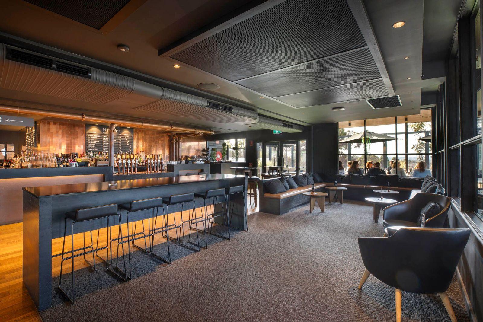 An event space in a pub with high tables, bar seating, lounge chairs, and large windows at The Rogue Squire.