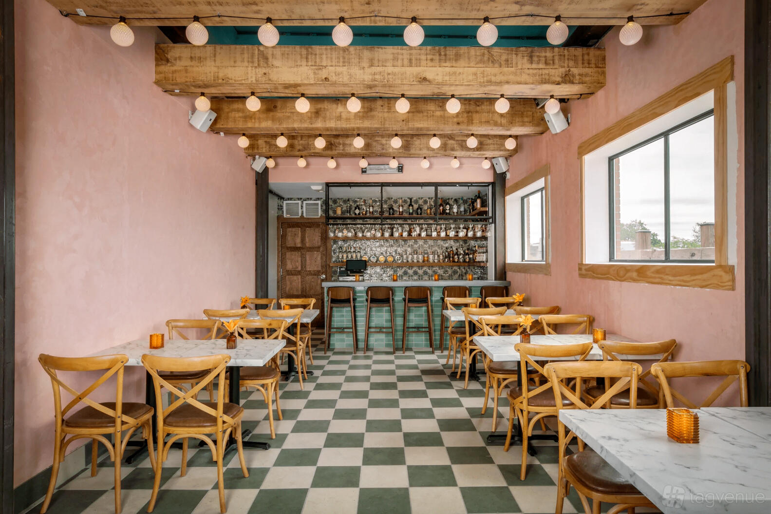 A rooftop dining area with checkered tile floors, wooden ceiling beams, marble tables, and globe pendant lights at Ambar Capitol Hill.