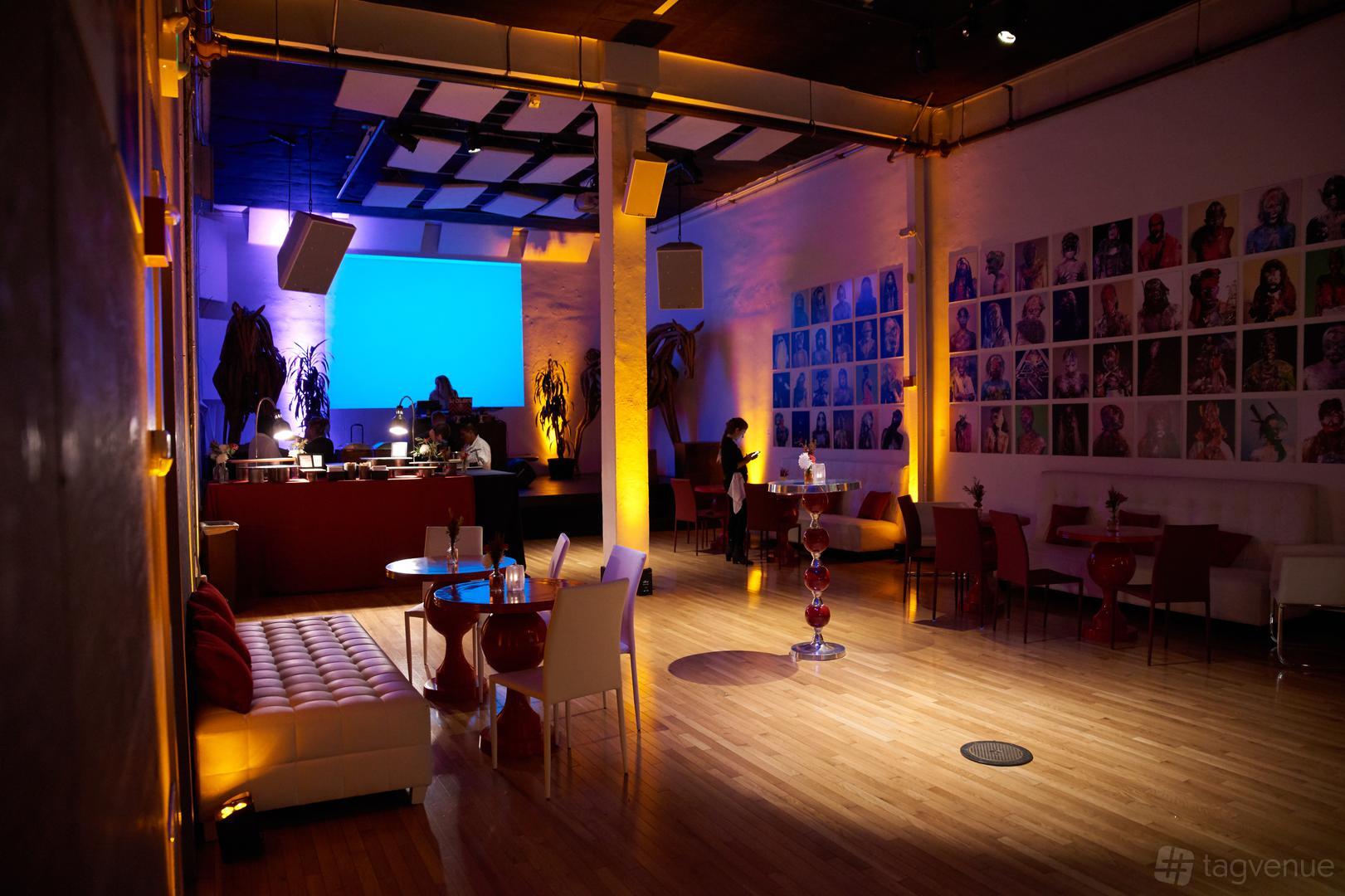 A gallery function room with a bar, ambient lighting, art-covered walls, and lounge seating at 111 Minna Gallery.