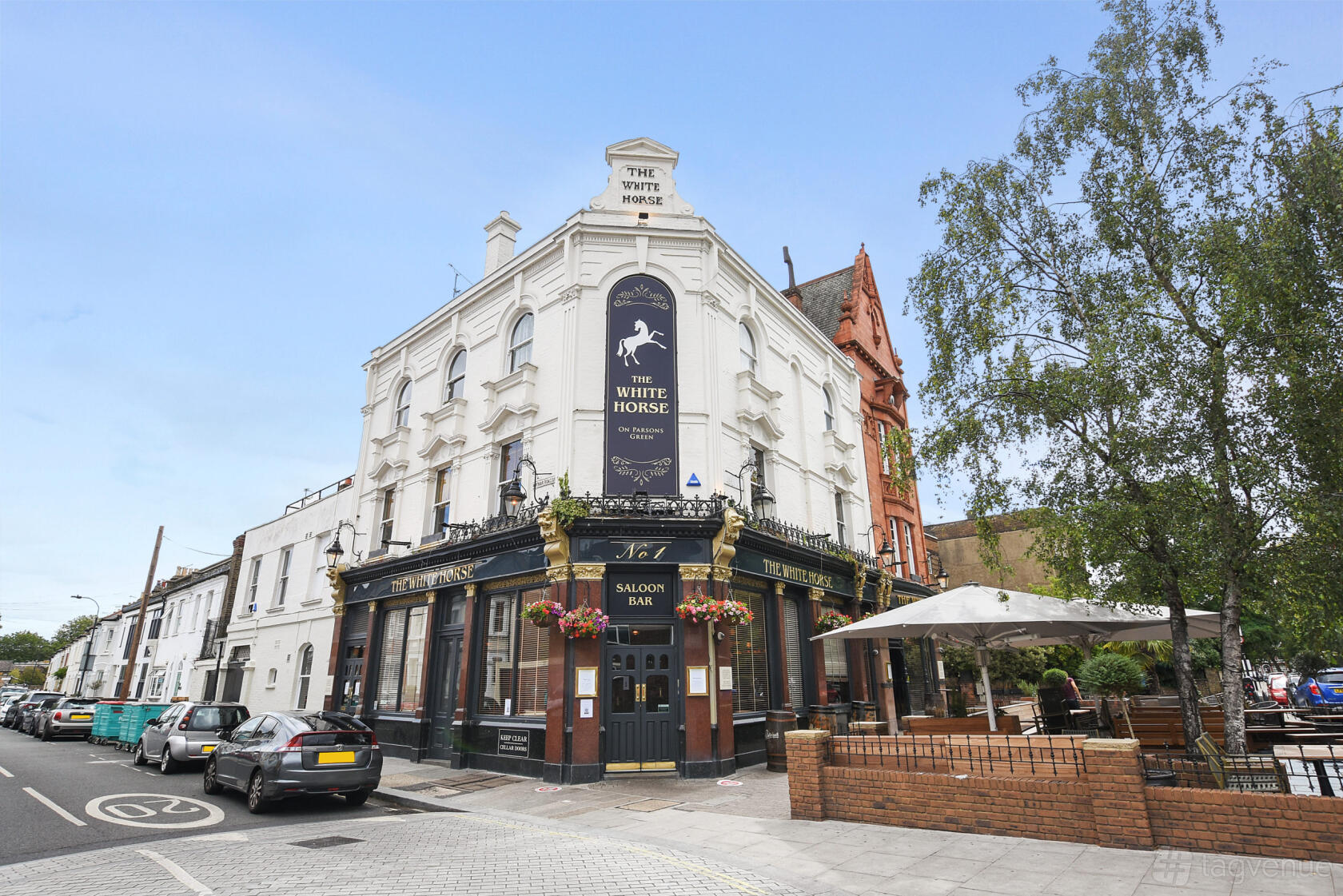 A corner pub with white brick facade, hanging flower baskets, and outdoor seating at White Horse, Parsons Green.