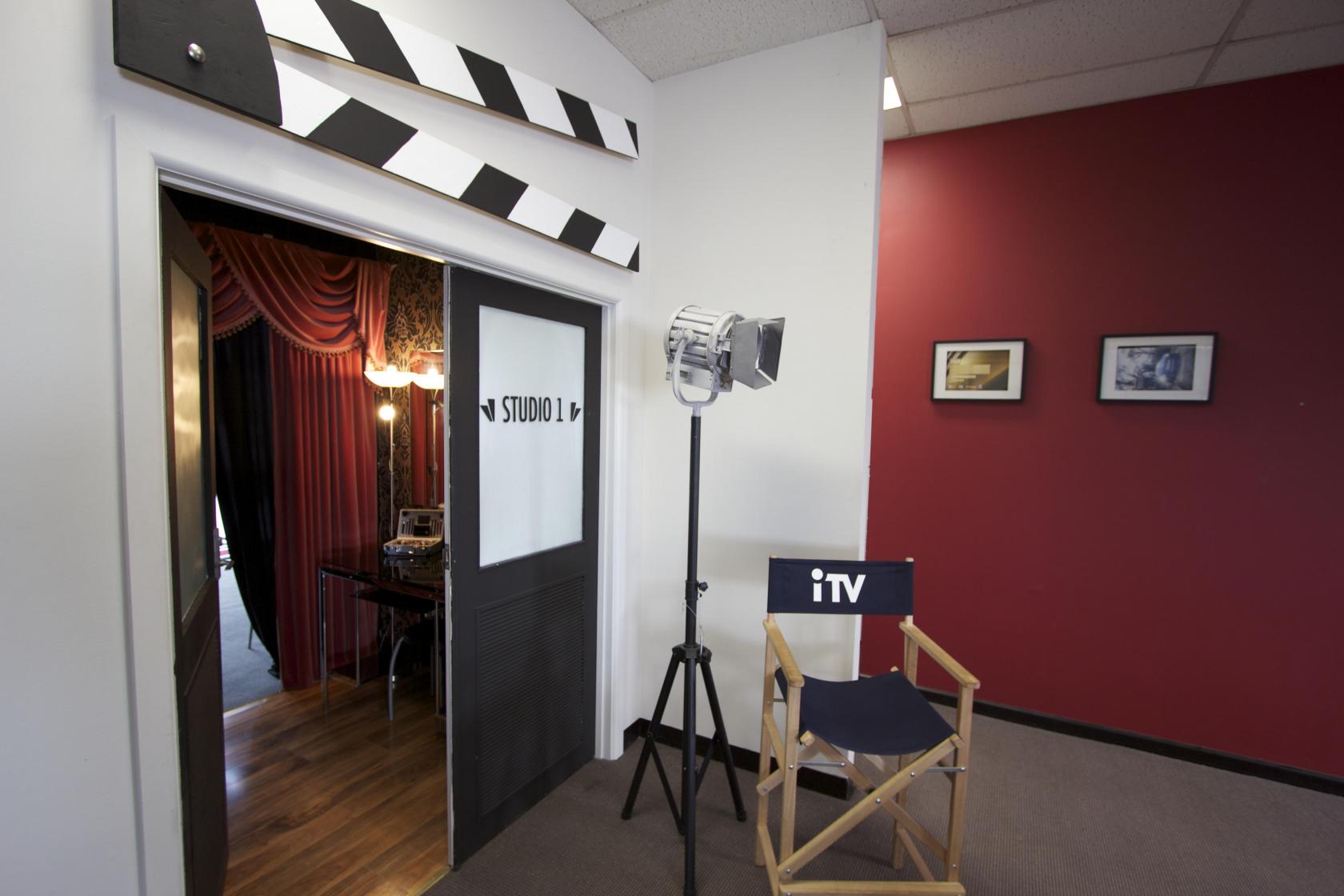 A photo studio with a director’s chair, stage light, and red curtains at the entrance at St Kilda Studio.