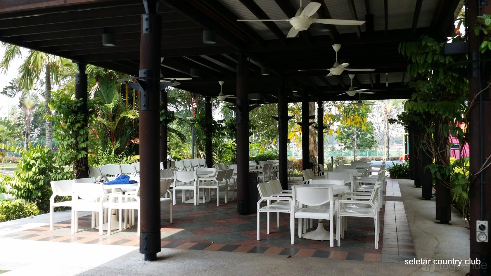An event venue with covered outdoor seating, white chairs, and ceiling fans at Seletar Country Club
