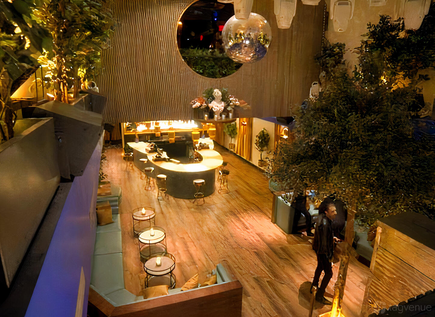 An event space in a nightclub with a central round bar, disco balls, wood flooring, and lounge seating at La Victoria.