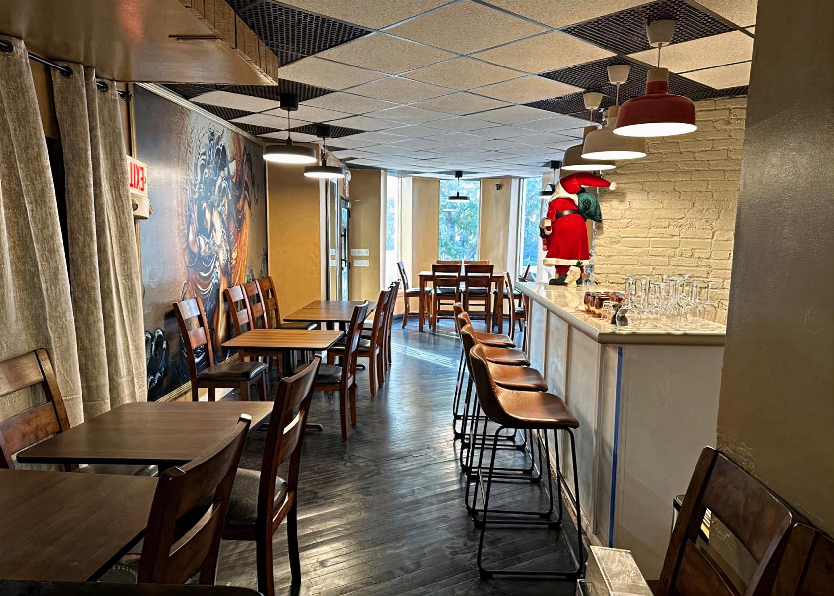An event space in a restaurant with wood tables, high-back chairs, a white brick wall, and pendant lighting at La Grotta DC.
