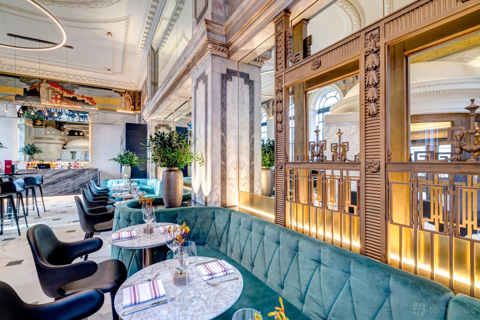 A hotel bar with velvet banquette seating, marble tables, and ornate decorative columns at Apex Temple Court.