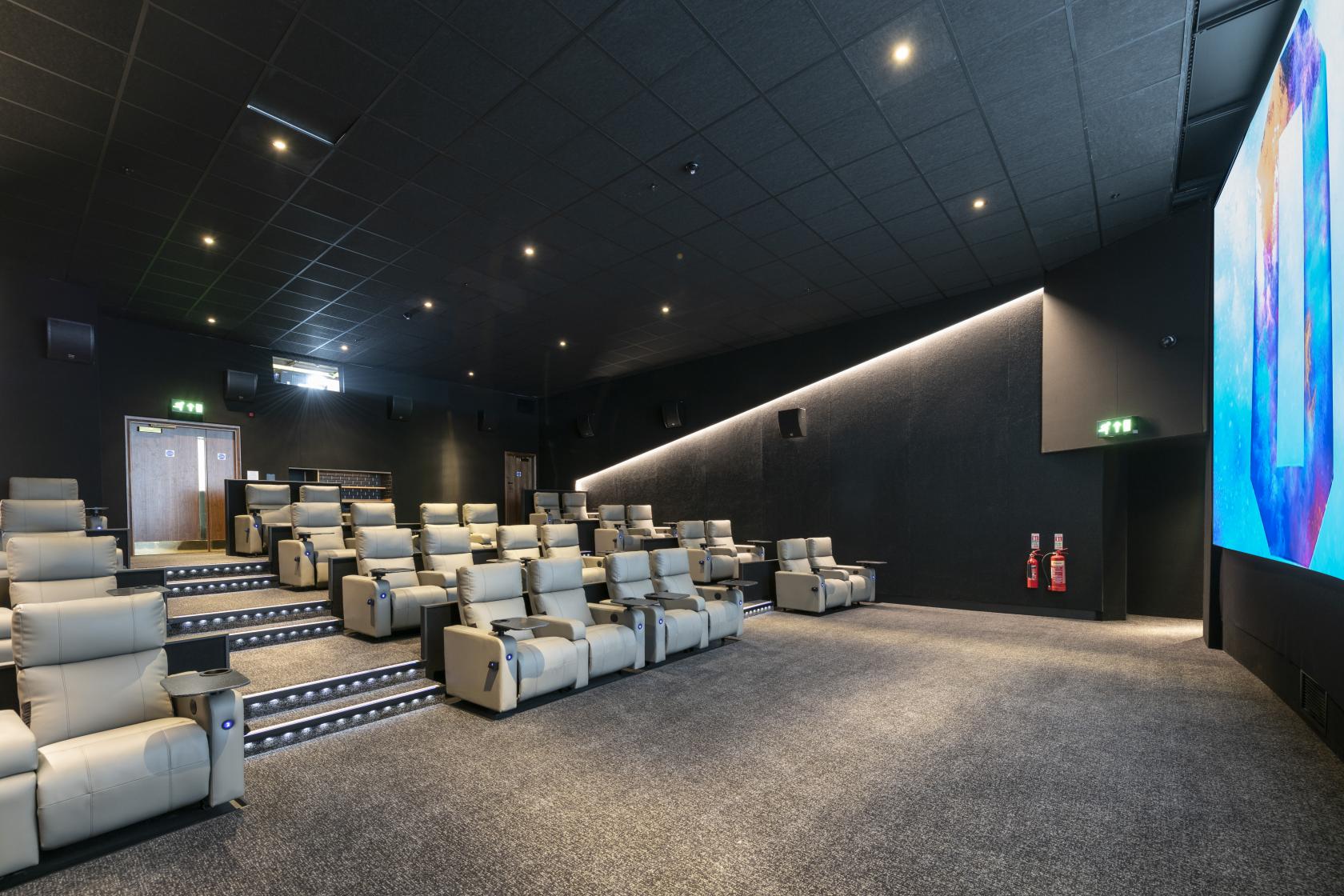 A cinema auditorium with tiered leather recliner seating and a large digital screen at ODEON LUXE Holloway.