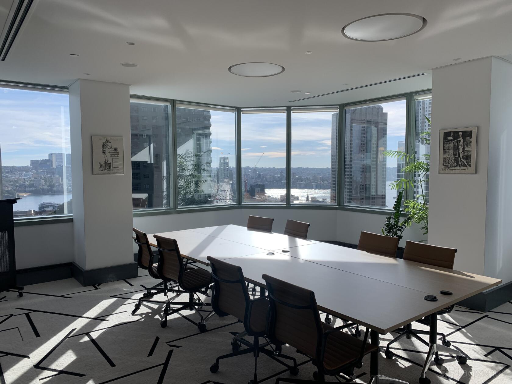 A meeting room with large windows, a long conference table, brown chairs, and city views at Royal Australasian College of Surgeons.