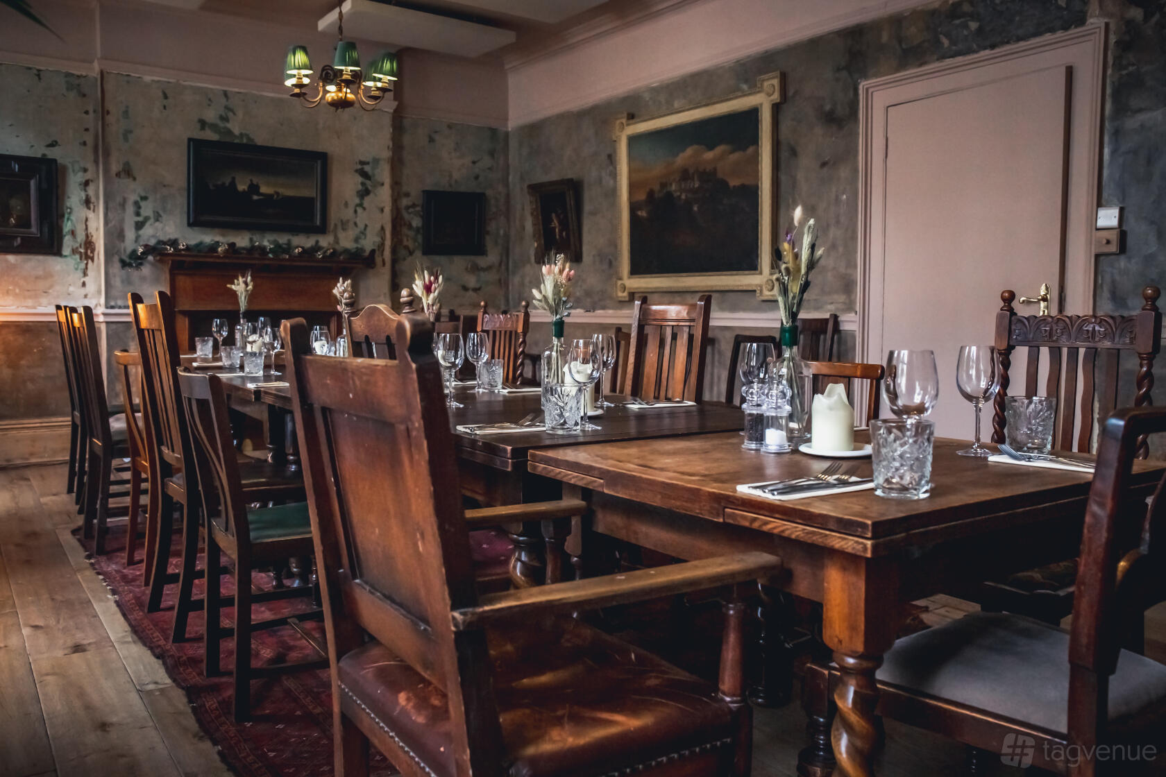 A dining room with wooden tables, antique chairs, and wall art at The Wilton Arms.