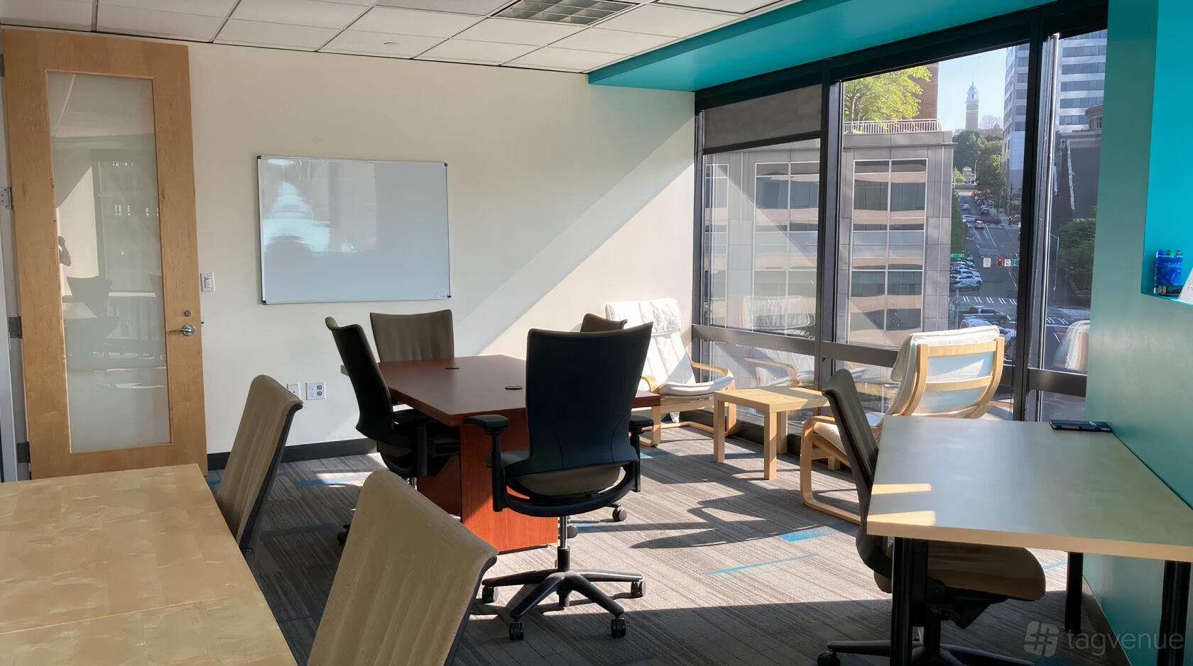 An office space with floor-to-ceiling windows, conference table, office chairs, and a whiteboard at SURF Incubator.