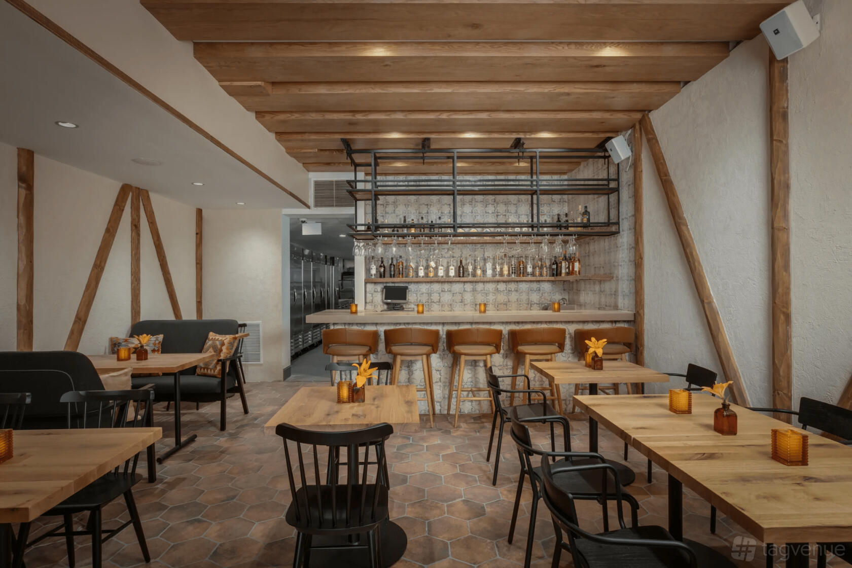 A restaurant dining room with wooden tables, black chairs, hexagonal floor tiles, and a tiled bar at Ambar Capitol Hill.