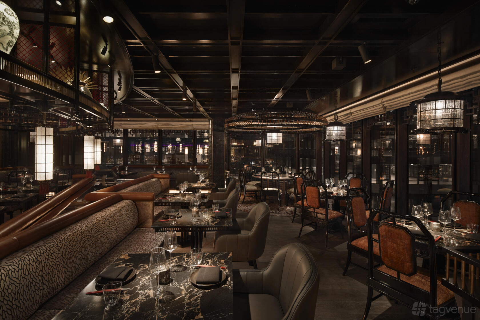 A restaurant with marble tables, plush seating, and ambient pendant lighting at TATTU London.