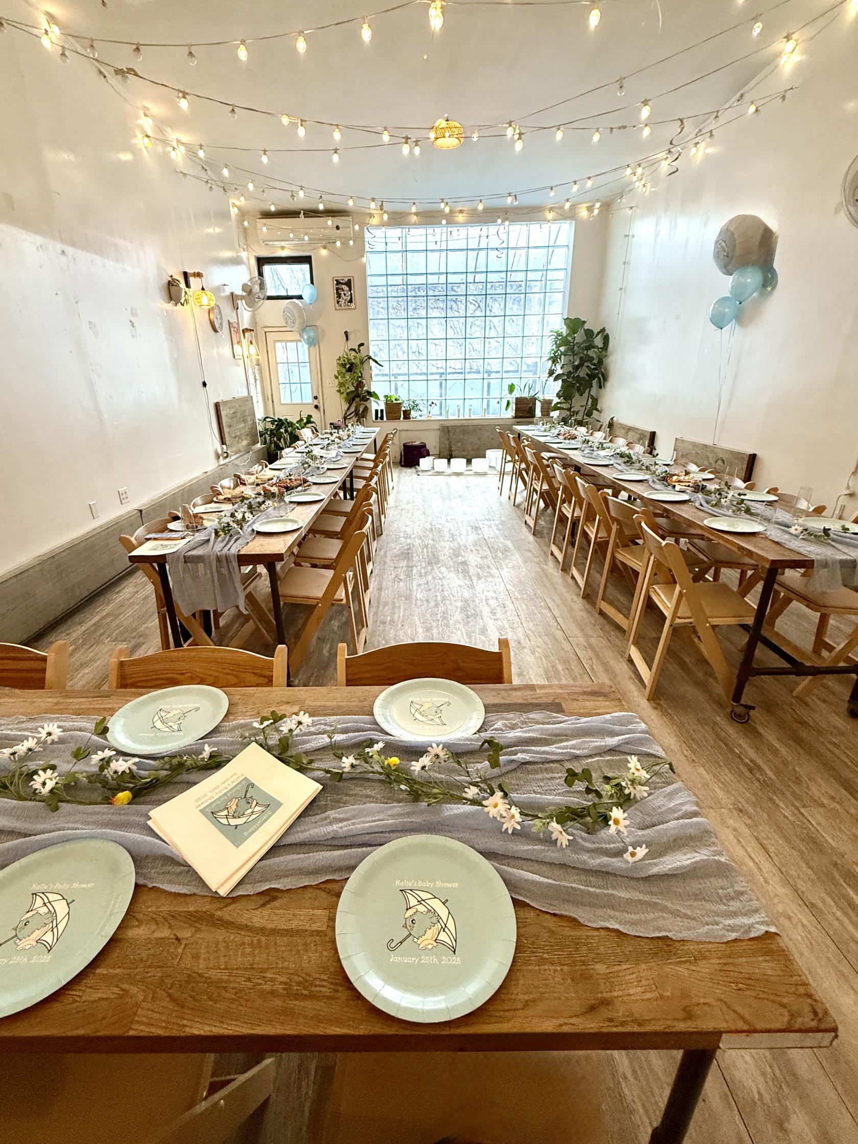 An event venue with long wooden tables, matching chairs, and decorative greenery at Bat Haus Coworking and Event Space.
