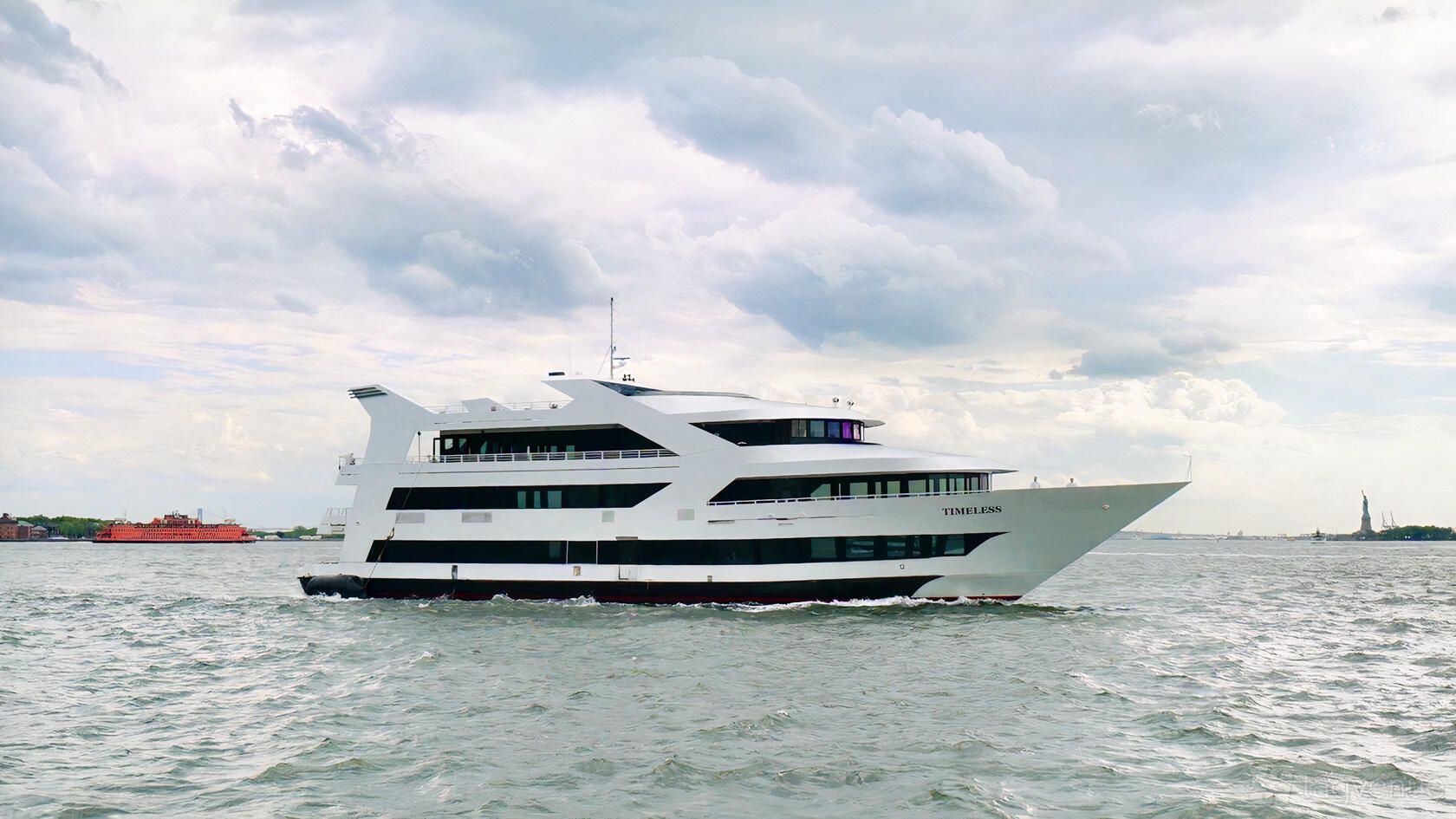 A multi-level boat with large windows and open decks cruising on the water at Empire Cruises Timeless.