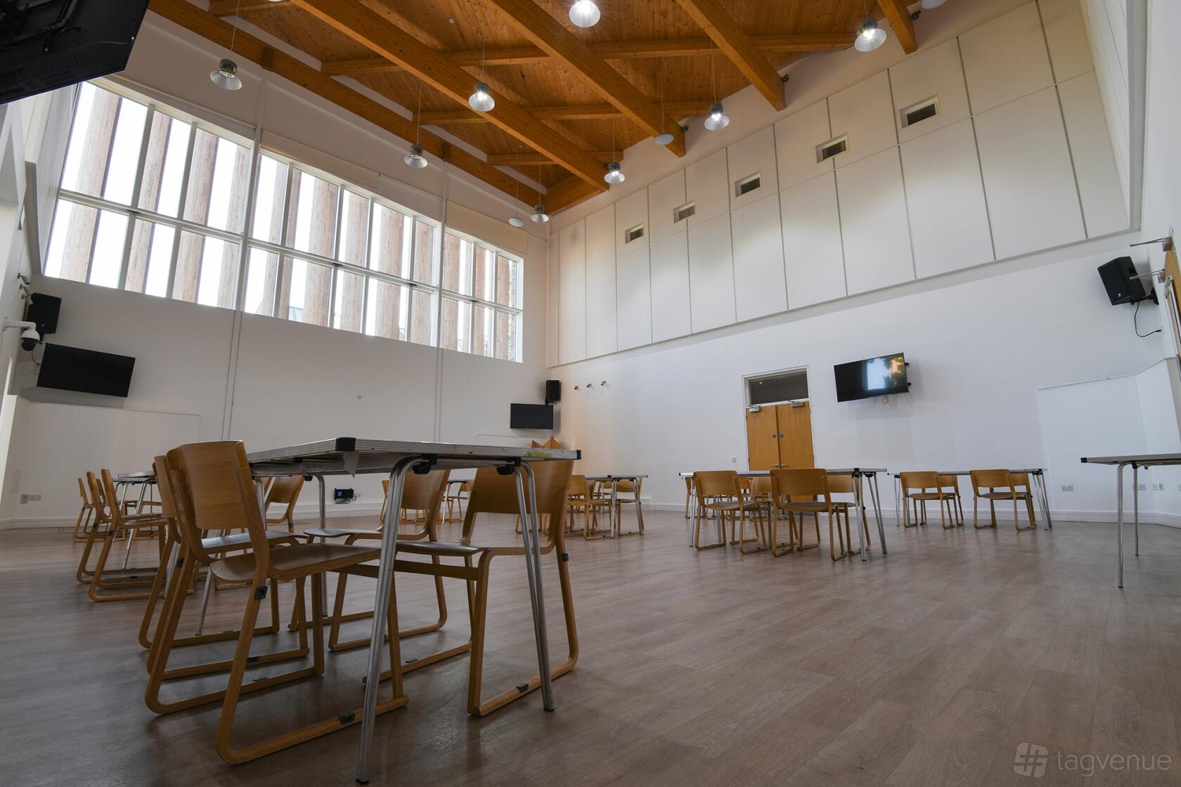 A community centre hall with high ceilings, exposed wood beams, and large windows at OneStonegrove.