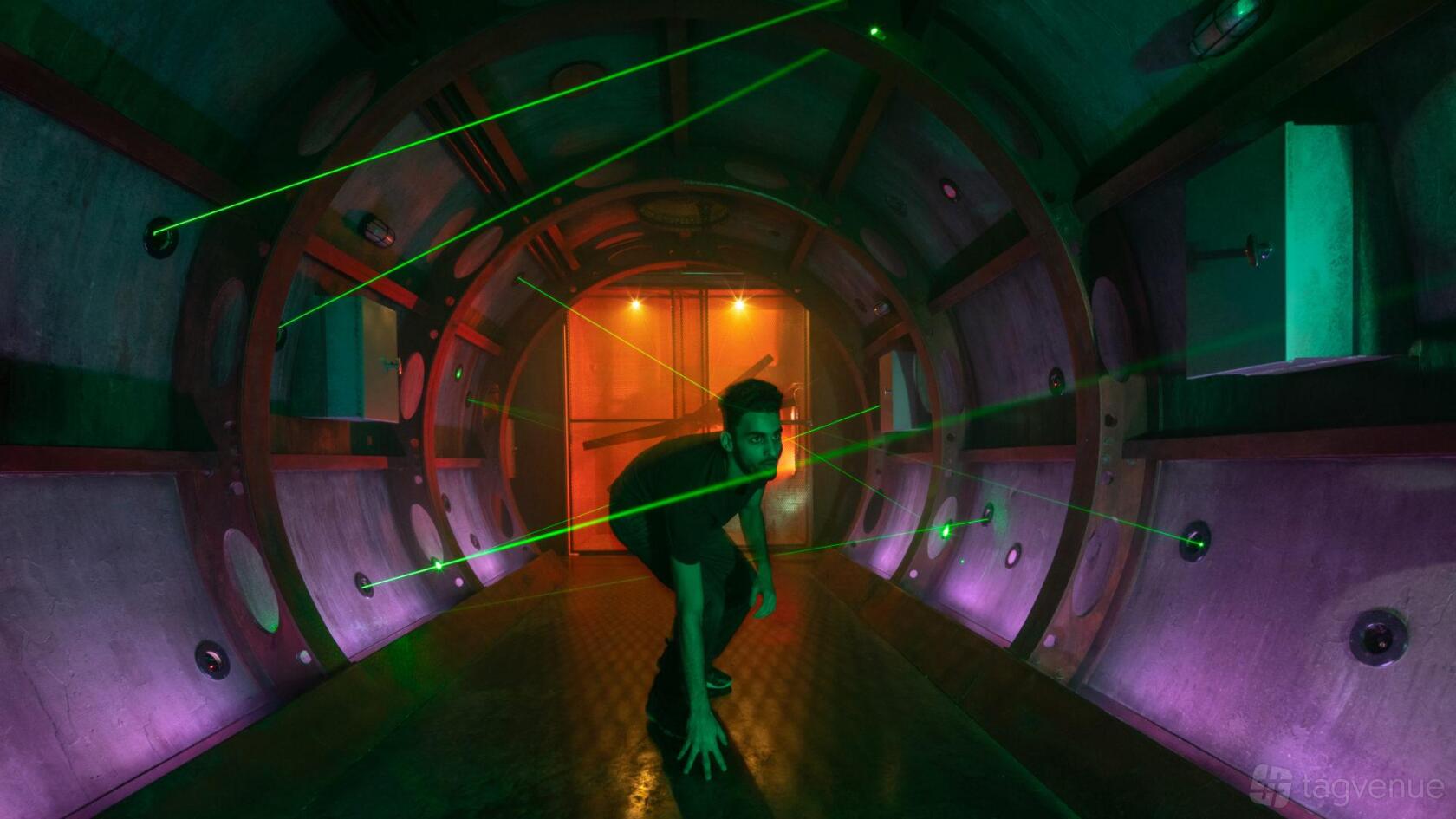 A themed function room with laser beams and tunnel walls illuminated by colored lights at 5 Wits - Arlington.