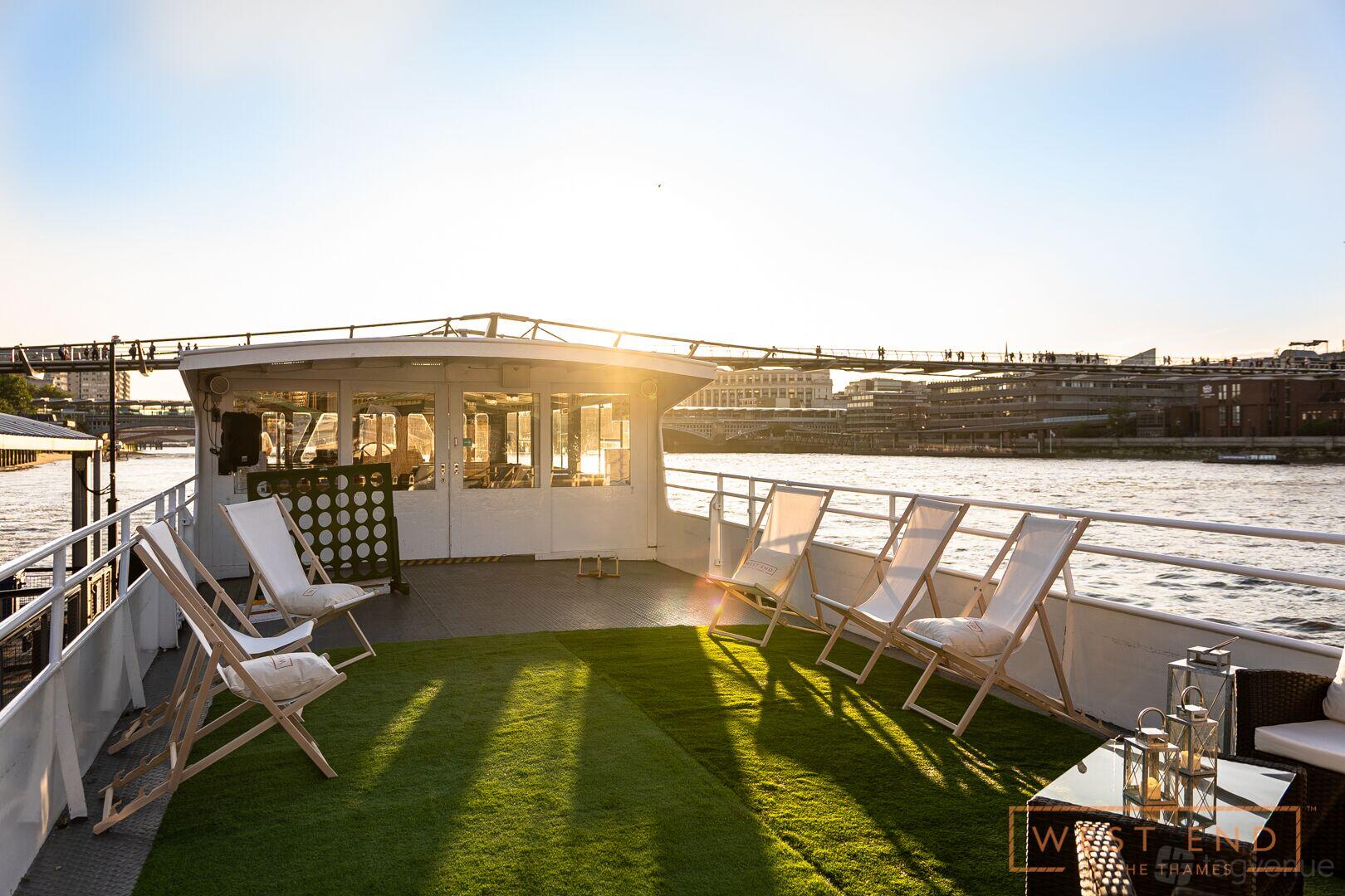A boat terrace with deck chairs, artificial grass flooring, and river views at West End on the Thames.