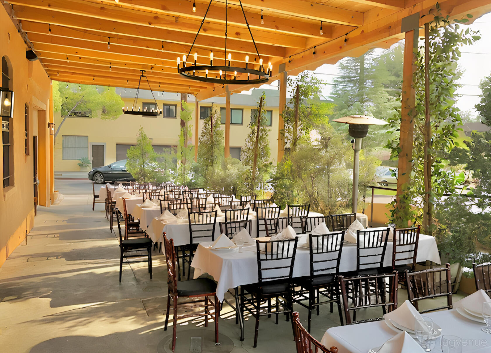 A covered patio with wooden beams, white table linens, and black chairs at Pinocchio's Pizza.