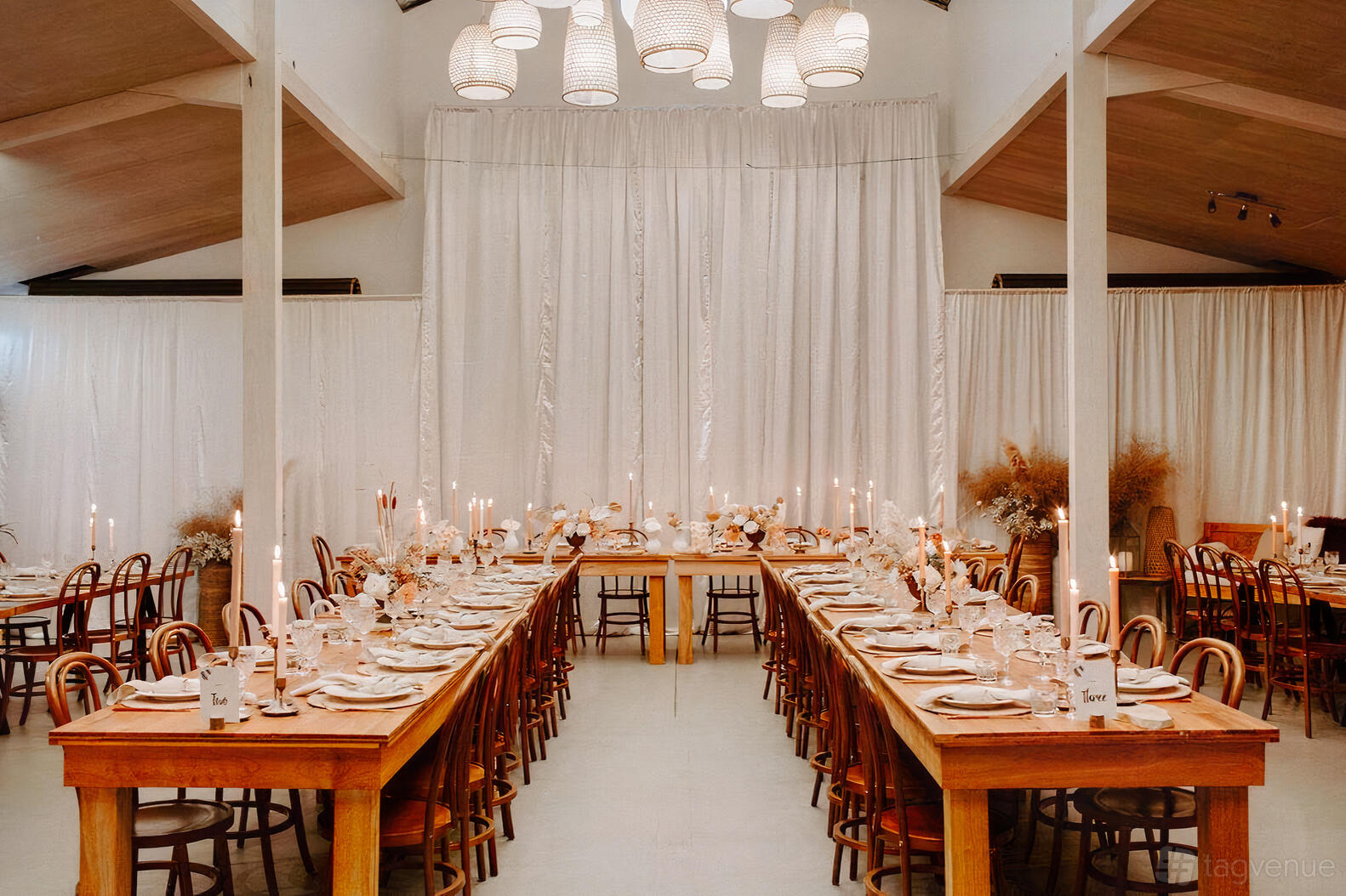 A barn with long wooden tables, bentwood chairs, and hanging woven pendant lights at Solitaire Homestead.