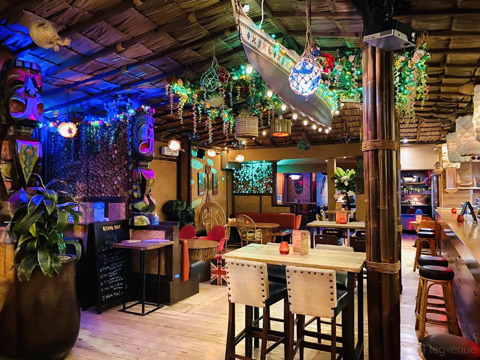 A tiki-inspired cocktail bar with bamboo furniture, tropical decor, and colorful mood lighting at Kona Kai.