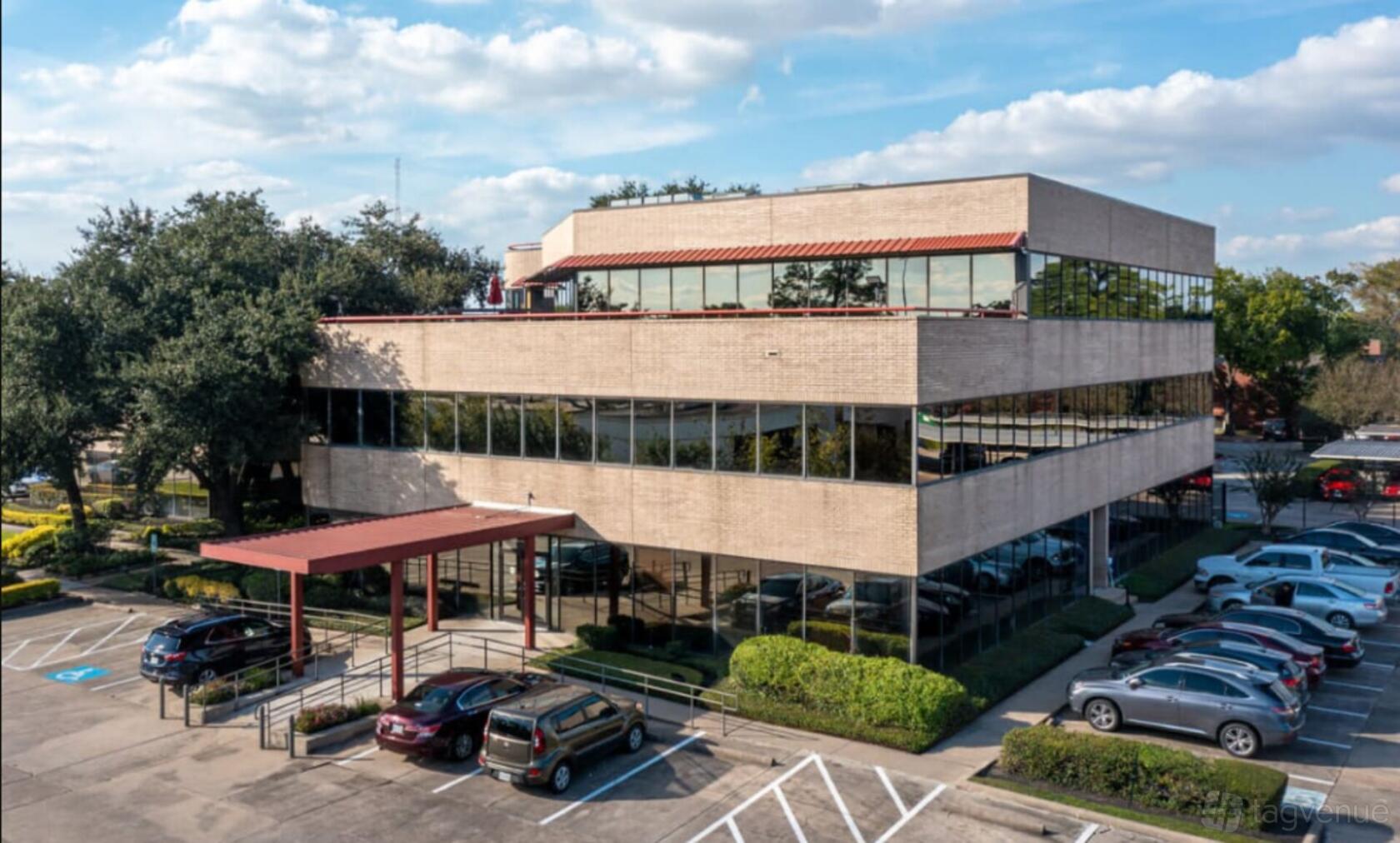 A meeting centre with a glass exterior, flat roof, and surrounding parking lot at Ranch Office.