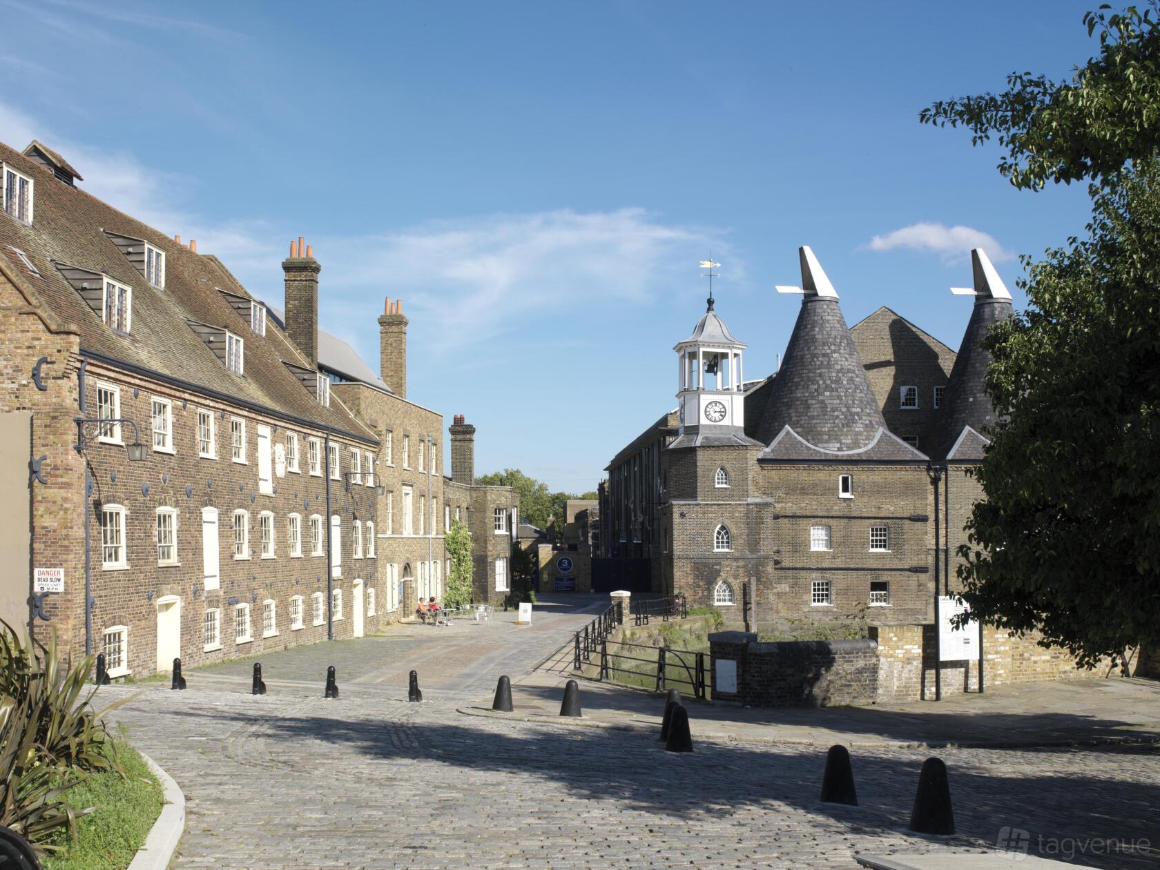 Historic brick buildings with distinctive oast house roofs and a clock tower at 3 Mills Studios.