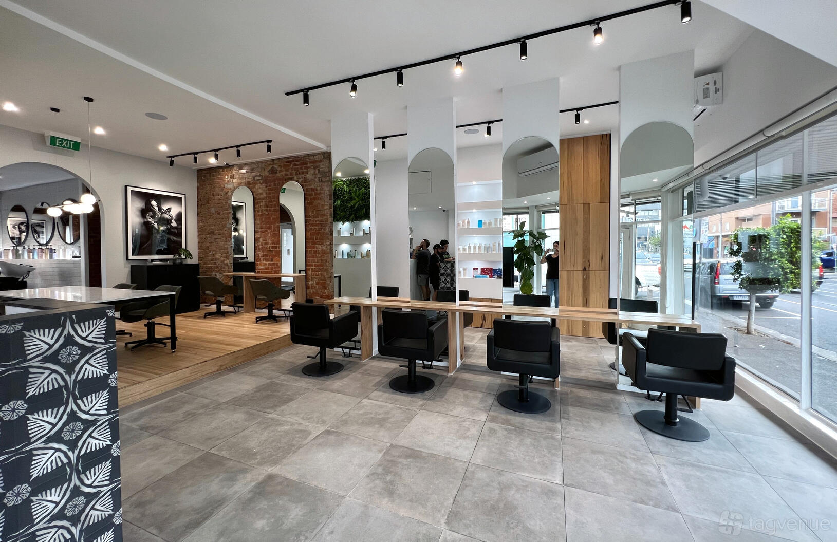 An event venue with salon chairs, large mirrors, exposed brick wall, and indoor plants at Flipped Hair Brunswick East.