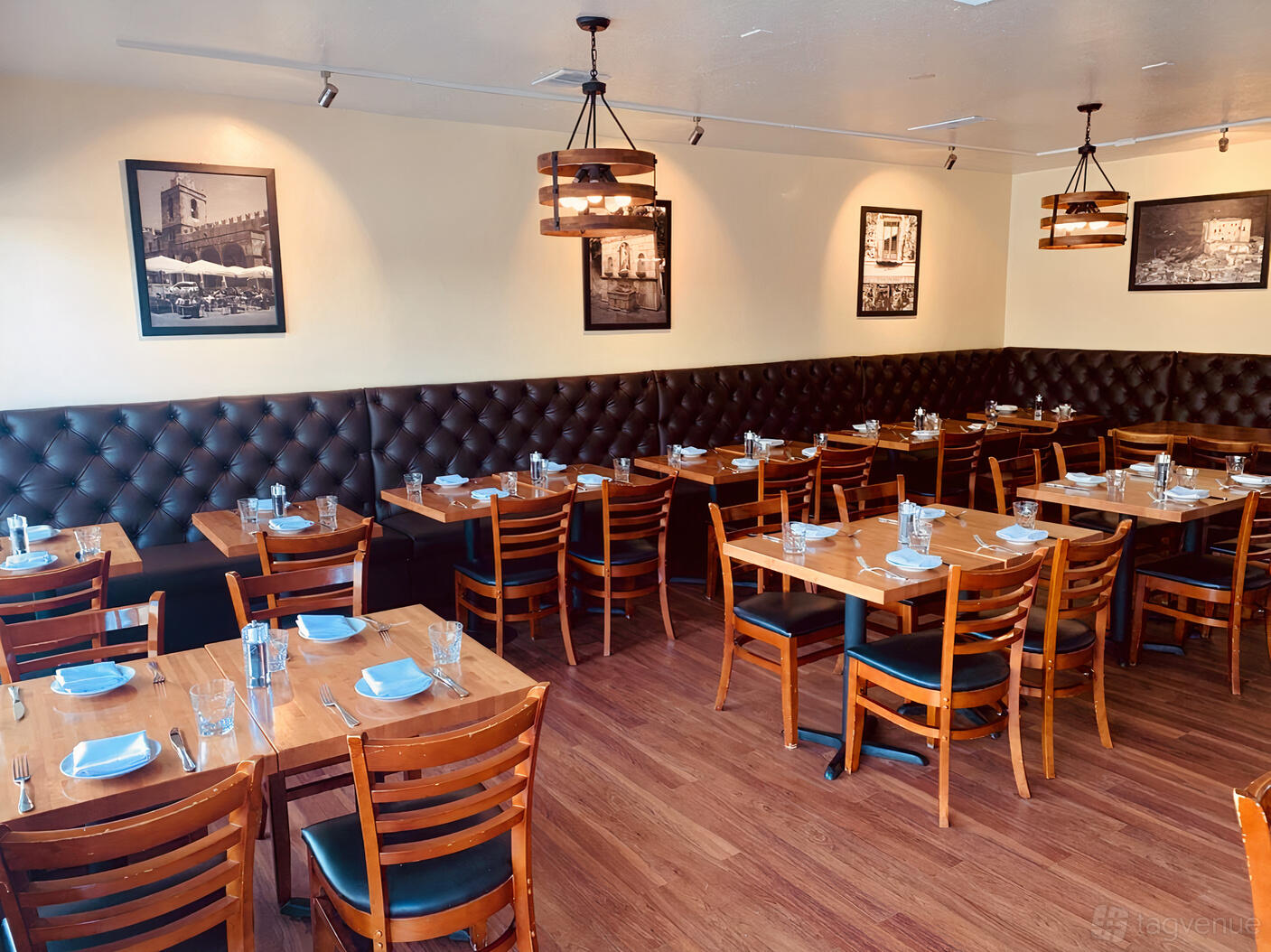 A restaurant dining room with wood tables, leather banquette seating, and framed black-and-white photos at La Stanza Cucina Italiana.